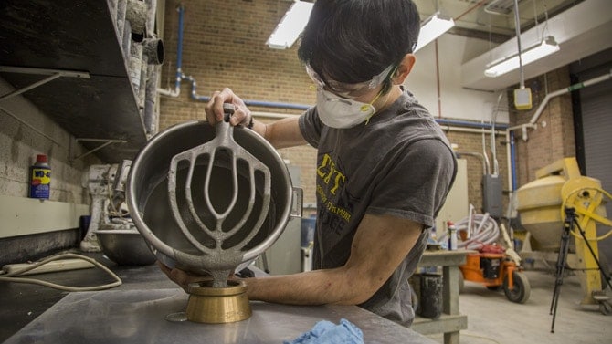 A person pours concrete out of a stand mixer