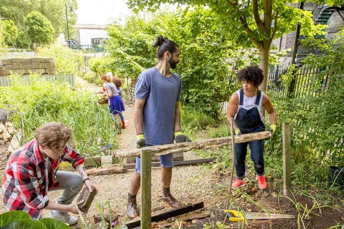 Four people work to build a fence in a community garden.