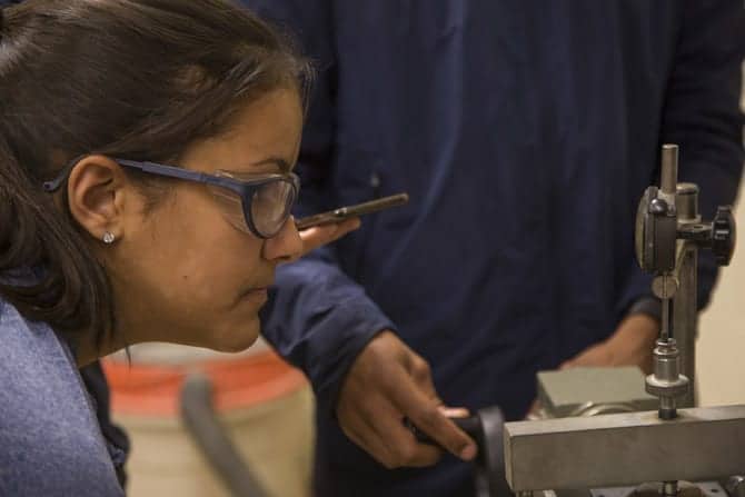 A student wearing safetfy googles closely examines a sheer apparatus