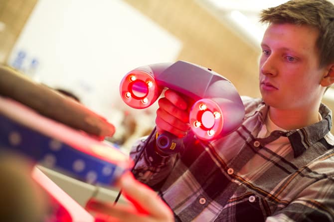 A person uses a handheld device with red light to scan an out-of-focus object