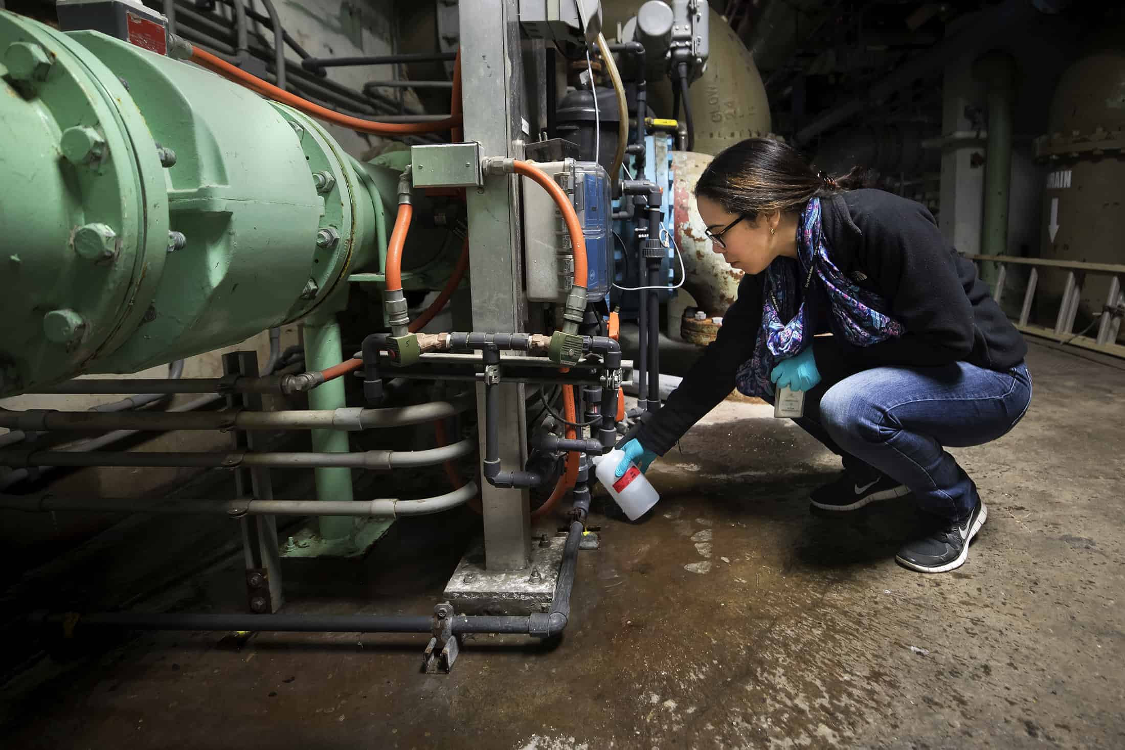 Person crouches to collect a water sample at a water treatment plant